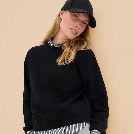 Felpa nera abbinata a camicia a righe e cappellino da baseball casual.