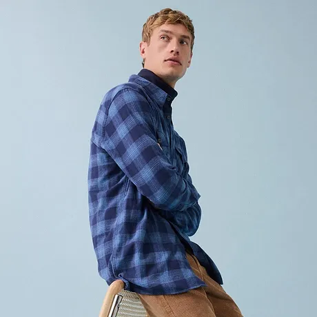 Camicia blu a quadri, pantaloni di velluto a coste marroni e sneaker bianche.