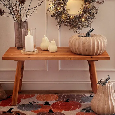 Decorazioni autunnali con zucche e ghirlande, colori caldi e materiali naturali dominano la scena.