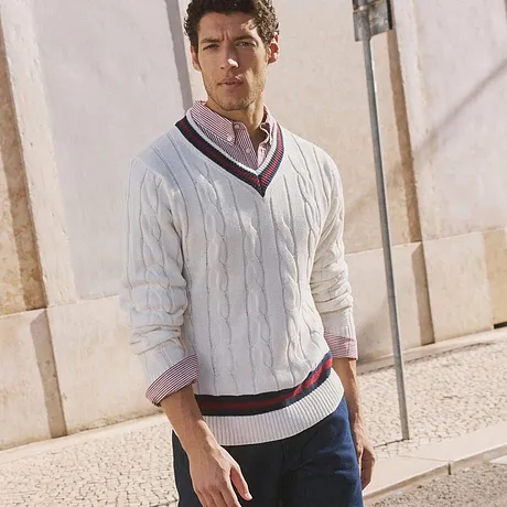Maglione bianco in maglia con scollo a V, jeans scuri e sneakers bianche. 