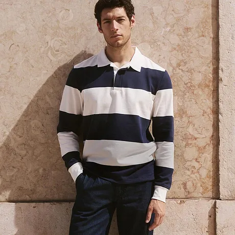 Look classico con felpa da rugby a righe, pantaloni scuri e sneakers bianche.