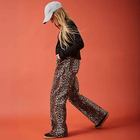 Un maglione nero incontra dei grintosi pantaloni leopardati. Un berretto bianco completa il look casual. 