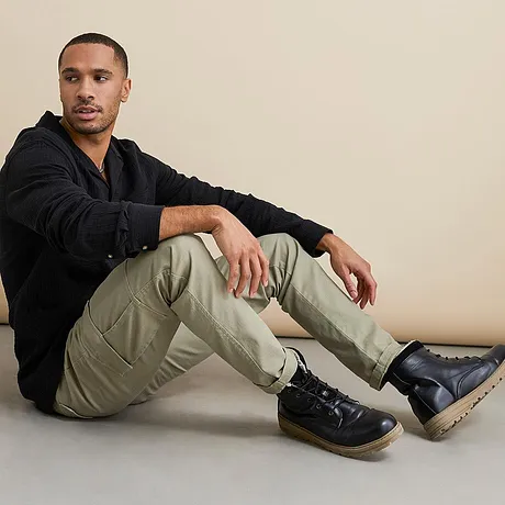 Top nero e pantaloni cargo beige abbinati a stivali stringati neri. 