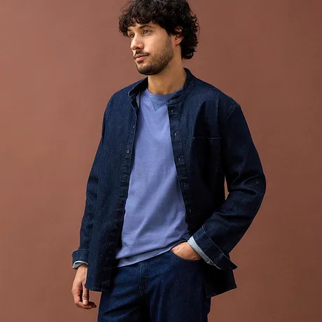 Camicia di jeans blu scuro e maglietta azzurra abbinate a pantaloni blu scuro.