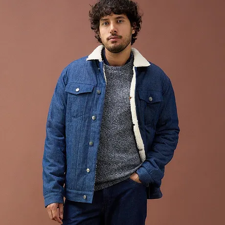 Giacca di jeans blu con fodera in pile, maglione grigio e jeans scuri.