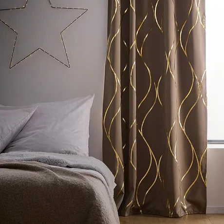 Eleganti tende con motivi dorati decorano la camera da letto.