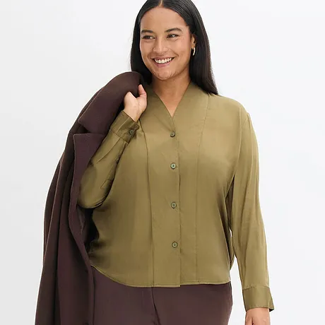 Elegante abbinamento di camicetta verde oliva e cappotto marrone.