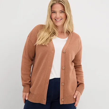 Cardigan color ruggine su top bianco, abbinato a jeans scuri.