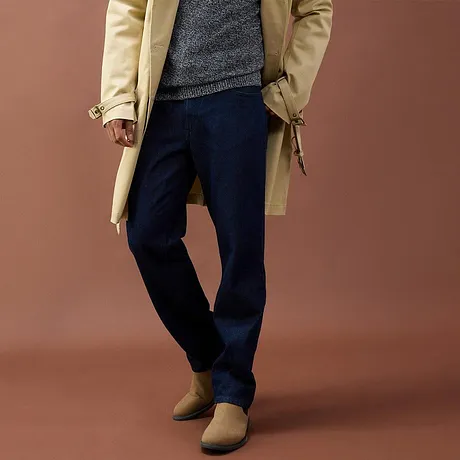 Trench beige, maglione grigio, pantaloni scuri e scarpe marroni.