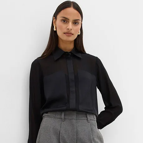 Camicetta nera abbinata a pantaloni grigi.