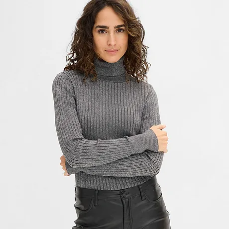 Maglione a collo alto grigio abbinato a pantaloni di pelle neri.