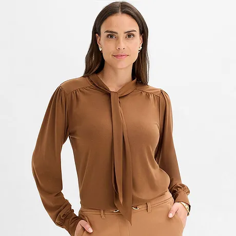 Maglia marrone con fiocco al collo e maniche lunghe.