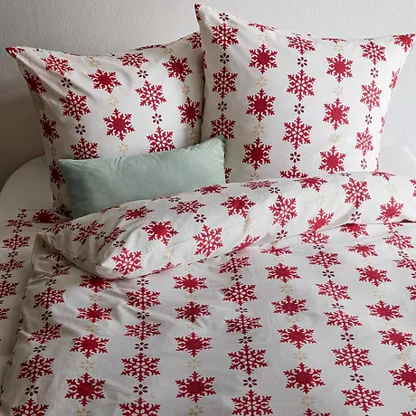 Biancheria da letto con fiocchi di neve rossi su fondo bianco. 