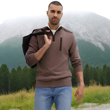 Un maglione marrone con zip e colletto, abbinato a jeans chiari.