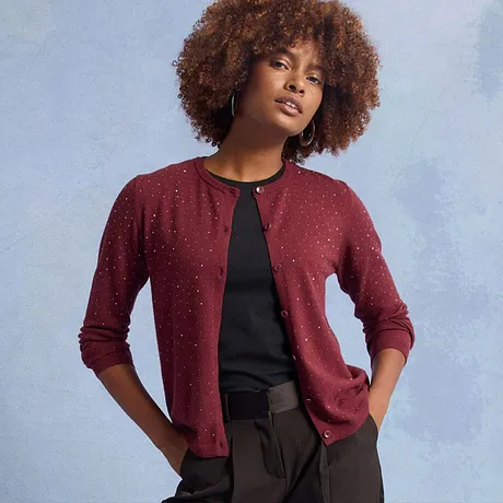 Cardigan rosso con decorazioni scintillanti, abbinato a un top nero.