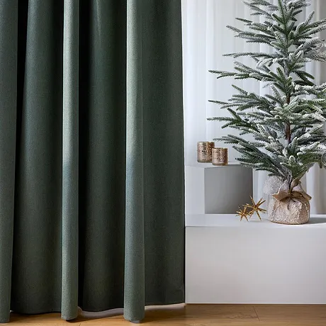 Tende scure incorniciano l'albero di Natale decorato.