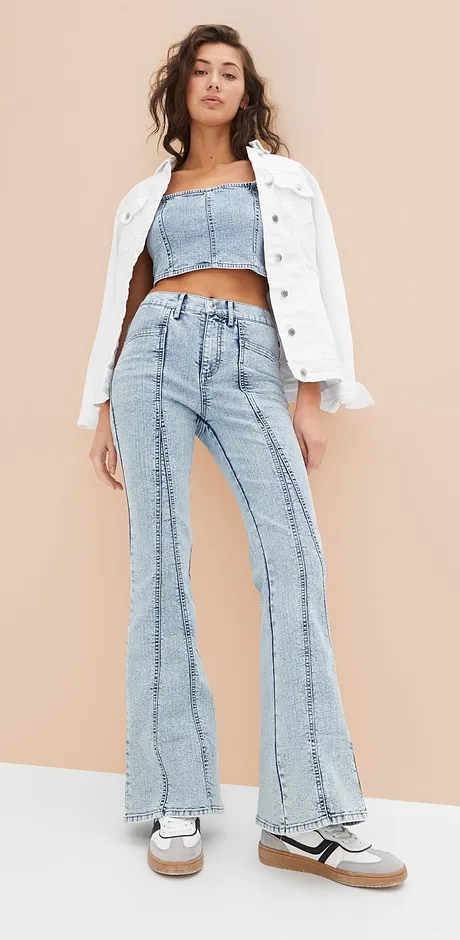 Outfit di tendenza con giacca di jeans bianca, top corto e jeans svasati in stile retrò. 