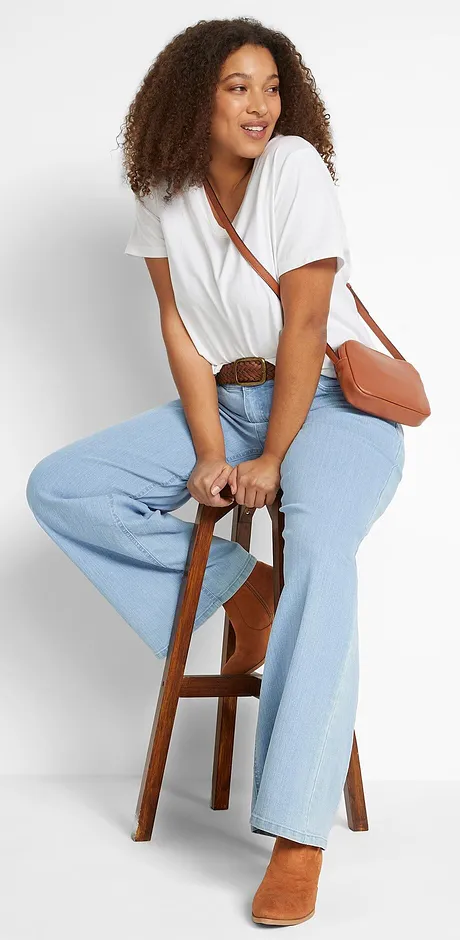 T-shirt bianca con scollo ampio, jeans chiari e borsa in pelle marrone.