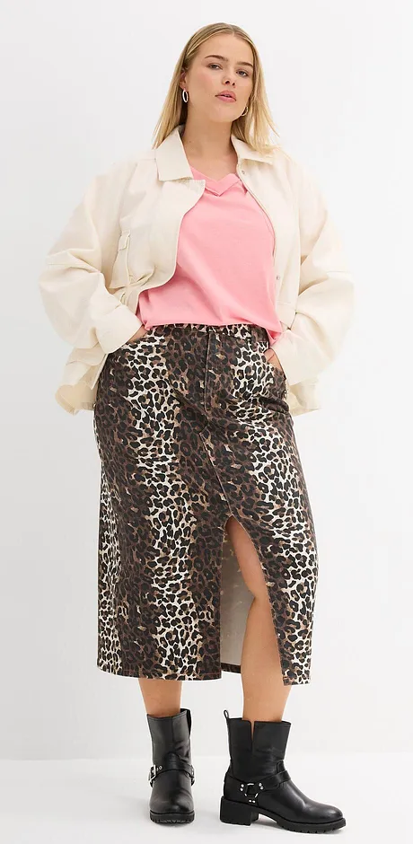 Giacca color crema, maglietta rosa, gonna con motivo leopardato e stivali neri creano un look elegante.