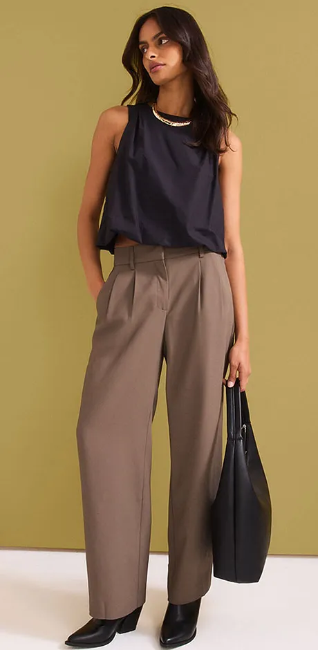 Outfit con top smanicato, pantaloni ampi beige e borsetta nera.