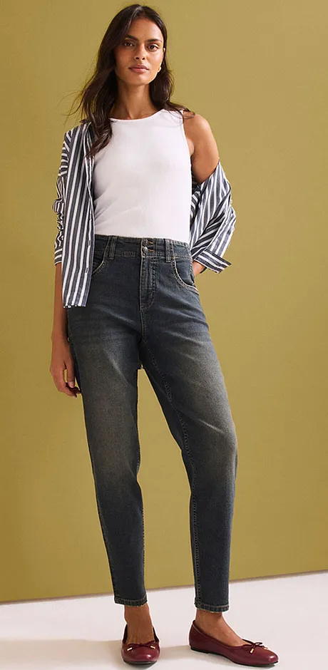 Top bianco, camicetta a righe, jeans a vita alta e ballerine rosse abbinate.