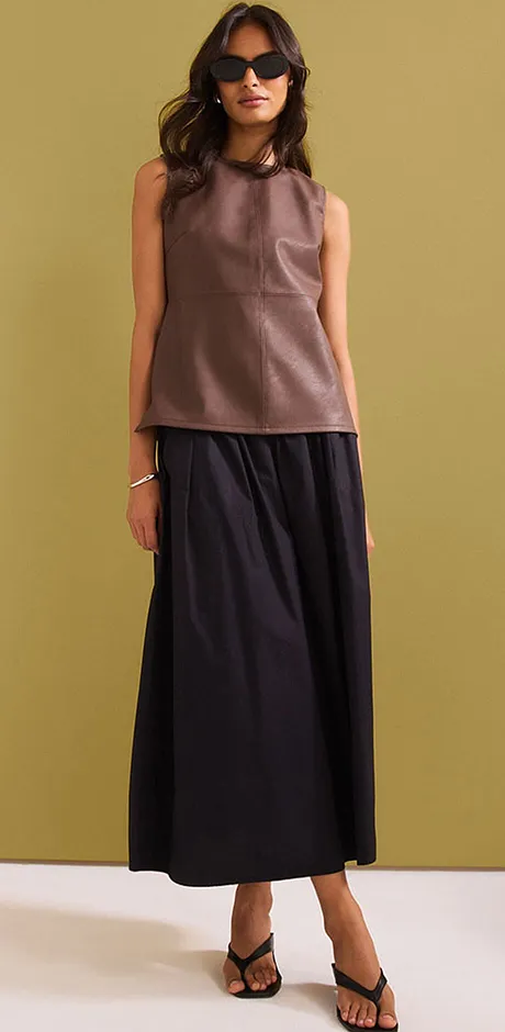 Outfit elegante con top marrone senza maniche e gonna lunga nera.