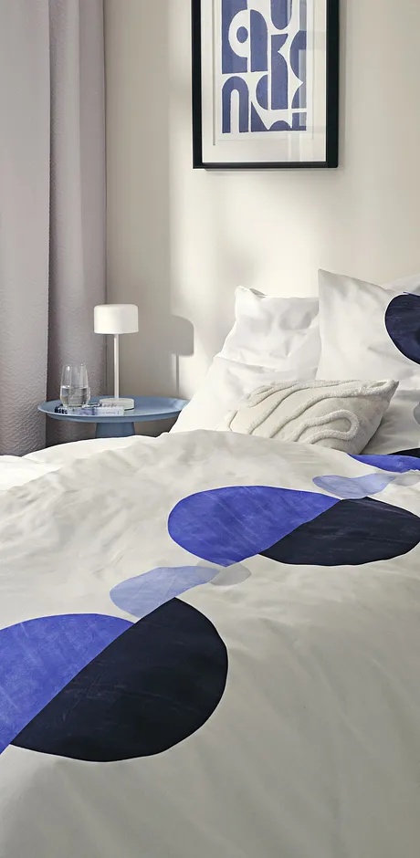 Biancheria da letto moderna con motivo geometrico in blu e nero su sfondo bianco.