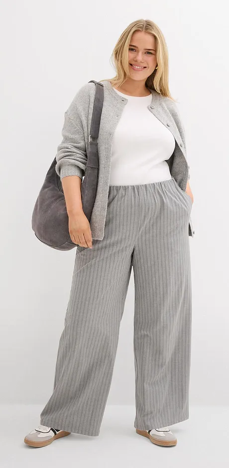 Cardigan grigio con top bianco e pantaloni grigi a righe.