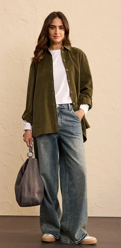 Look composto da camicia oversize verde oliva, maglietta bianca e jeans larghi.