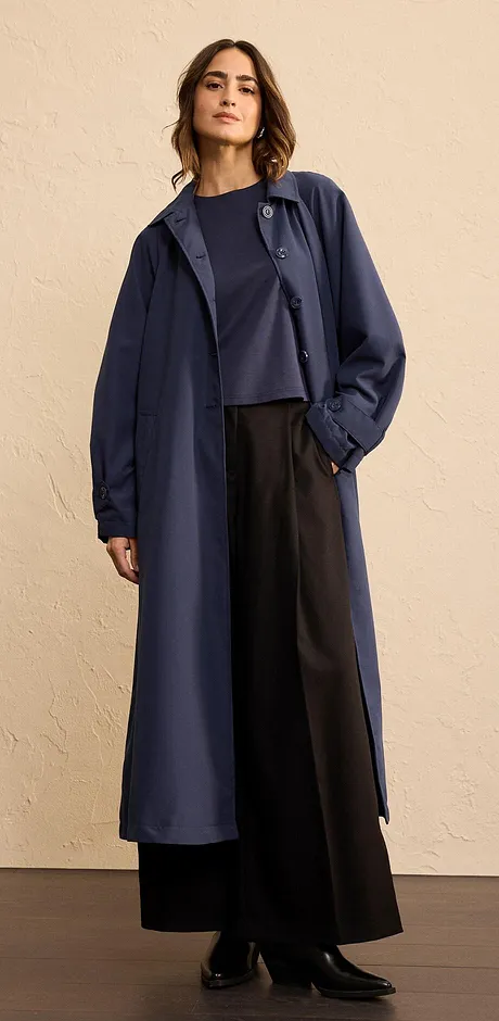 Elegante cappotto lungo blu scuro, abbinato a pantaloni larghi e top semplice.