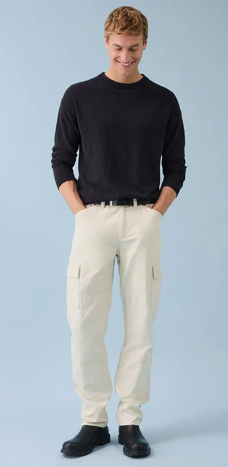 Look classico: maglione scuro abbinato a pantaloni cargo chiari.