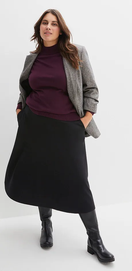 Giacca grigia, maglione viola e gonna lunga nera con stivali neri.