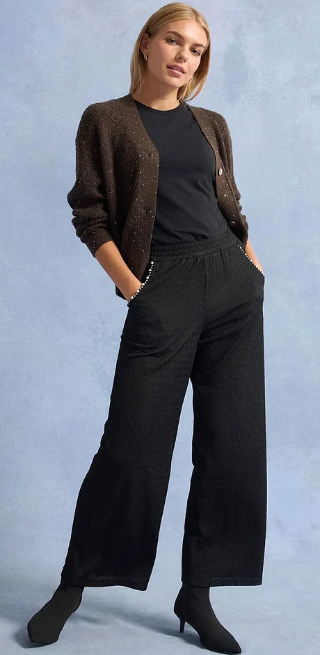 Pantaloni neri, maglietta e cardigan scintillante.