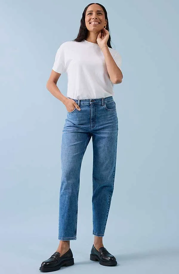Look casual con t-shirt bianca, jeans blu e scarpe nere.