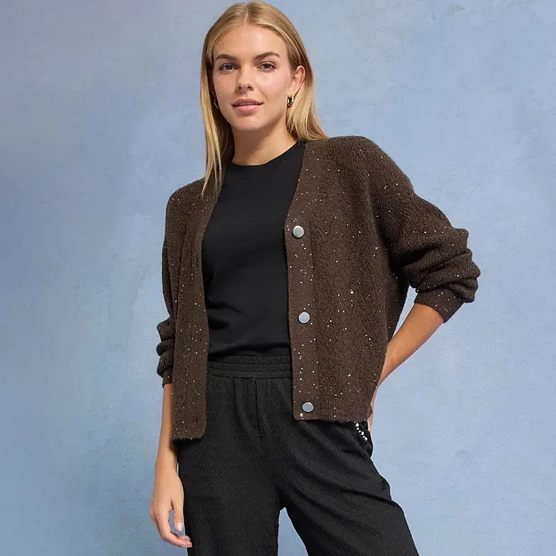 Cardigan marrone scintillante su un outfit nero.