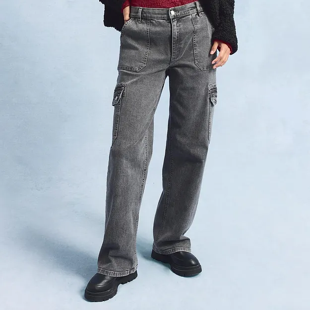 Jeans cargo grigi con ampie tasche laterali, abbinati a scarpe nere.