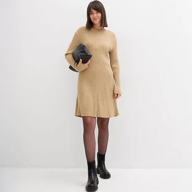 Elegante abito in maglia beige con scollo rotondo e maniche lunghe. Abbinato a una pochette nera.