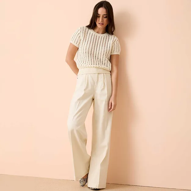 Top a maniche corte lavorato all'uncinetto abbinato a pantaloni larghi e fluidi.