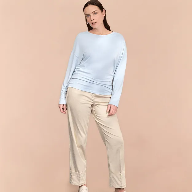 Maglione leggero azzurro e pantaloni beige.