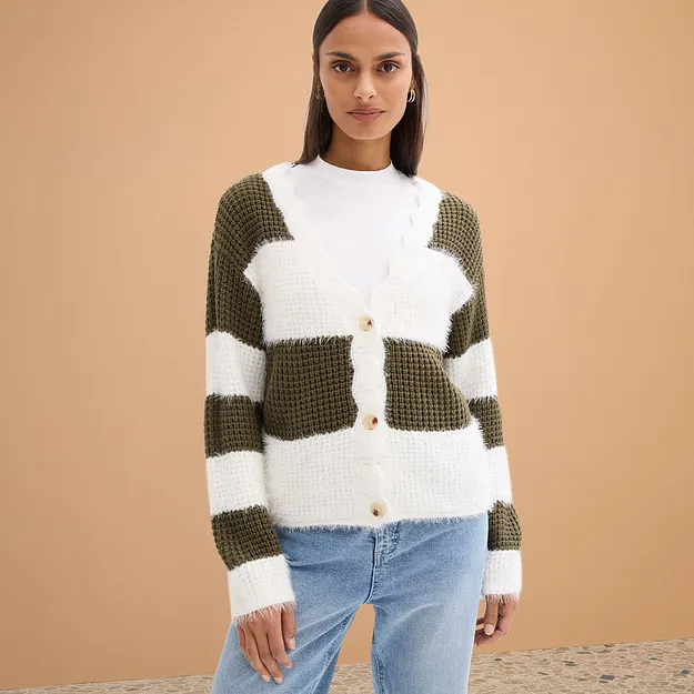 Cardigan lavorato a maglia nei colori bianco e verde oliva, abbinato a jeans azzurri.