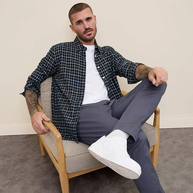 Camicia a quadri sopra una maglietta bianca, pantaloni grigi e sneaker bianche. 