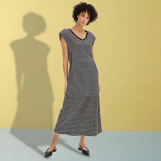 Elegante abito lungo a righe bianche e nere con scollo a V e ballerine nere.