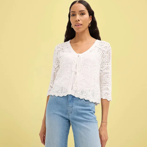 Cardigan bianco lavorato all'uncinetto con maniche a tre quarti abbinato a jeans blu.