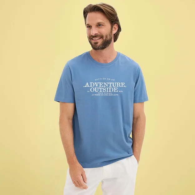 Maglietta blu casual con una stampa bianca e pantaloni chiari.