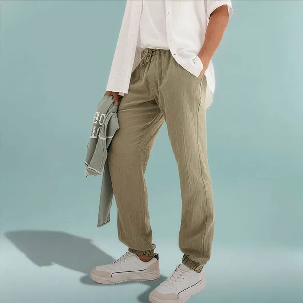 Pantaloni comodi verde oliva abbinati a una camicia bianca e una felpa chiara.