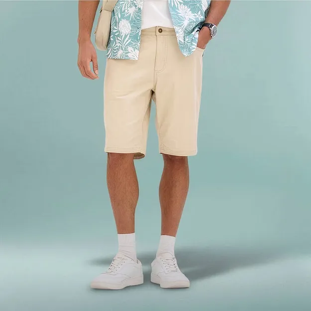 Un look estivo disinvolto con bermuda beige, camicia a fantasia e sneakers bianche.