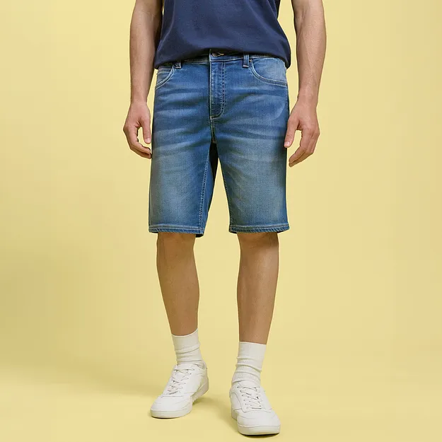 Bermuda di jeans casual e maglietta blu abbinati a scarpe da ginnastica bianche e calzini.