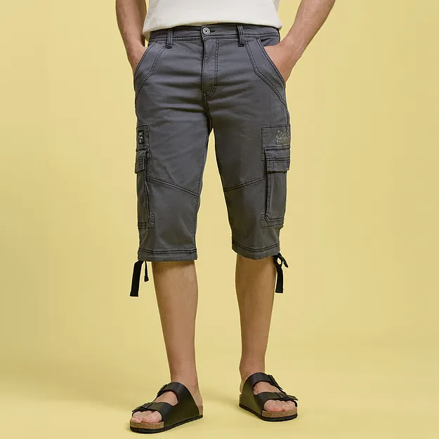 Pantaloncini cargo grigi con pratiche tasche laterali, maglietta bianca e sandali neri.