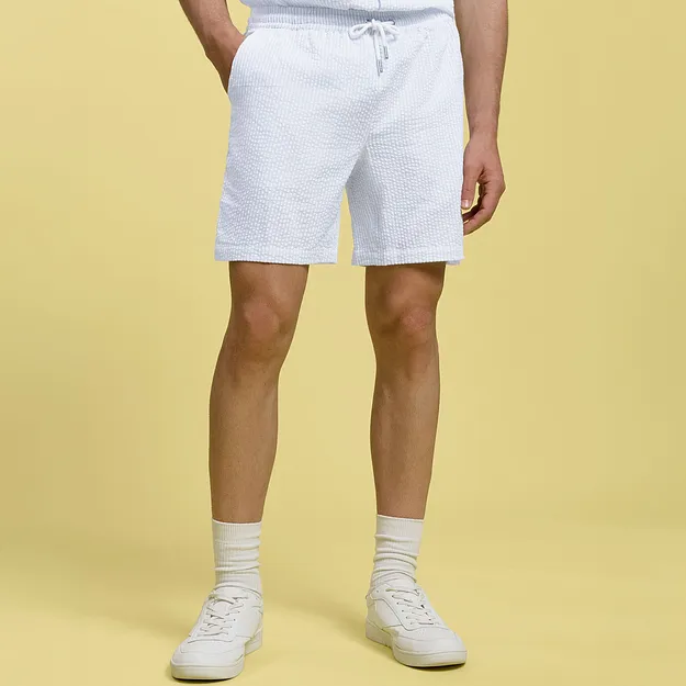 Bermuda bianchi con coulisse, calzini bianchi e scarpe da ginnastica.