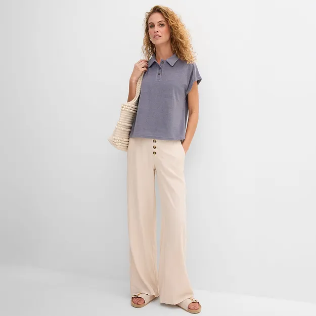 Una donna elegante indossa una maglietta blu ampia e pantaloni larghi beige in stile casual.